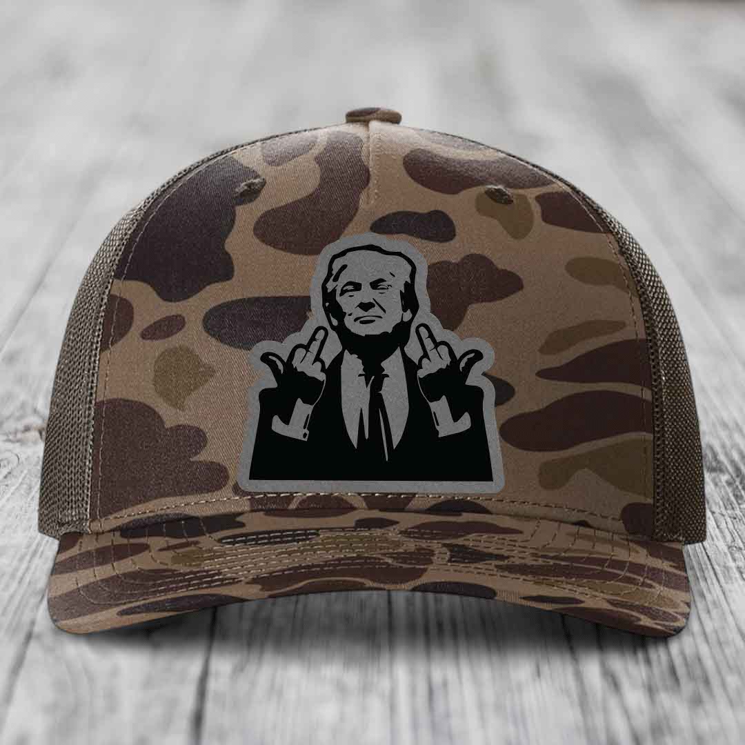 Camouflage trucker hat with black and grey patch of man making rude hand gestures.