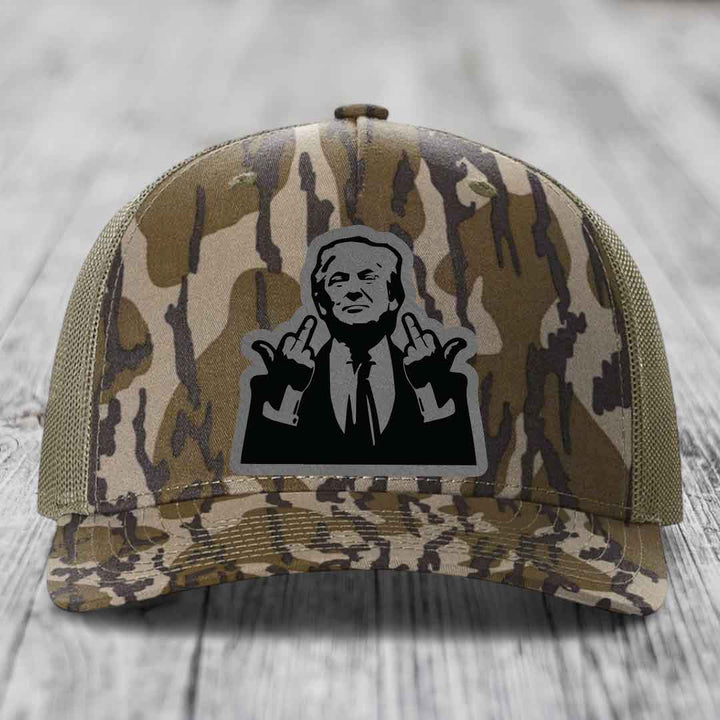 Camouflage trucker hat with black silhouette patch of man giving middle finger gesture.