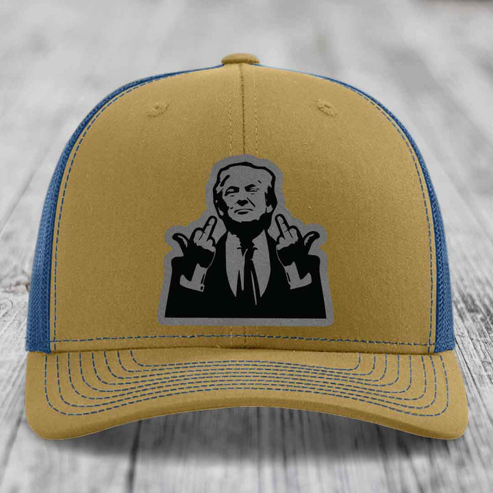 Two-tone trucker hat with tan front and blue mesh back, featuring a black-and-grey graphic patch of a man making hand gestures.