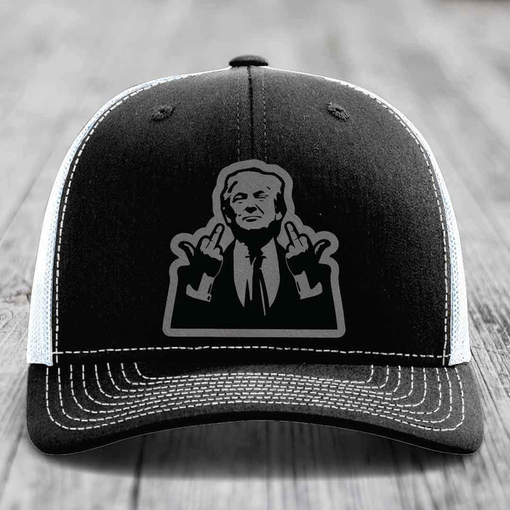 Black trucker hat with white stitching and a graphic patch of a man making hand gestures.