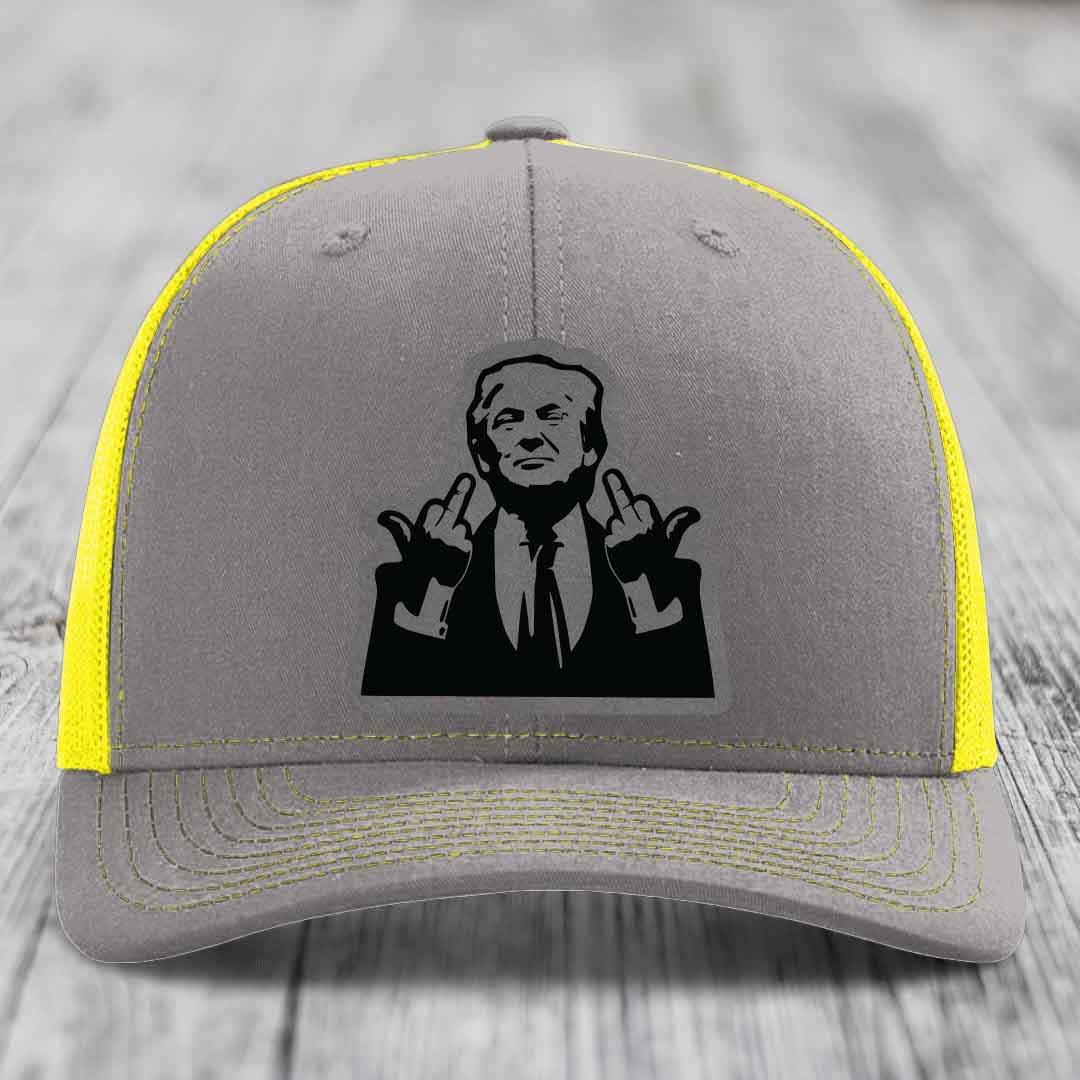 Grey trucker hat with yellow mesh and stitching, featuring a black patch of a man making rude hand gestures.