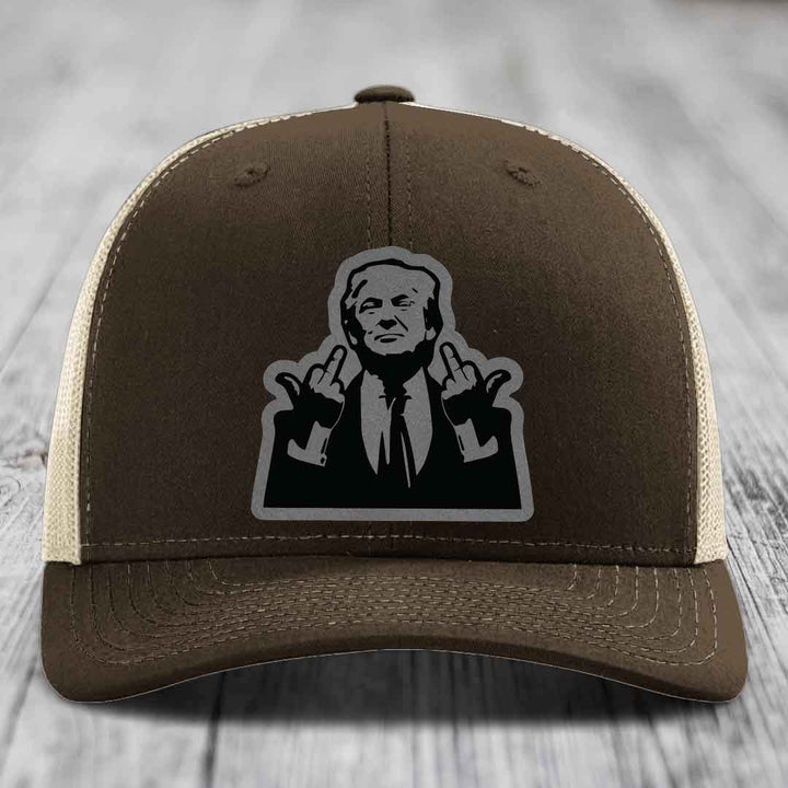 Brown trucker hat with beige mesh back and black-and-gray graphic patch of a man making hand gestures.