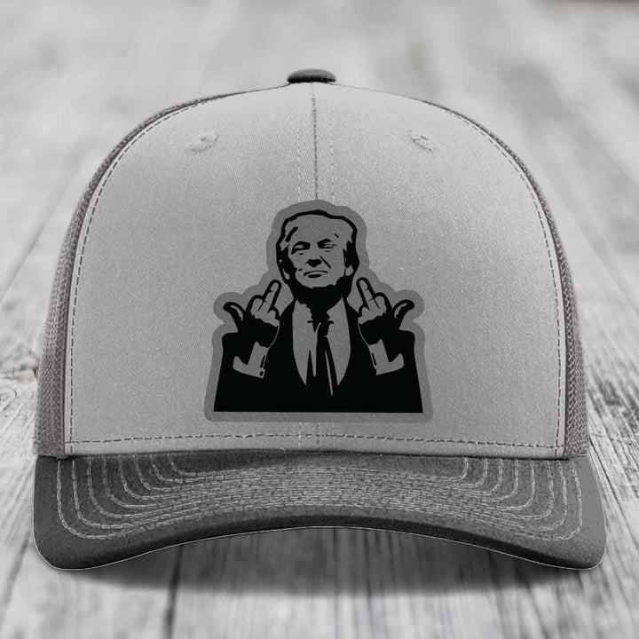 Grey trucker hat with black leatherette patch of man giving middle finger gesture.