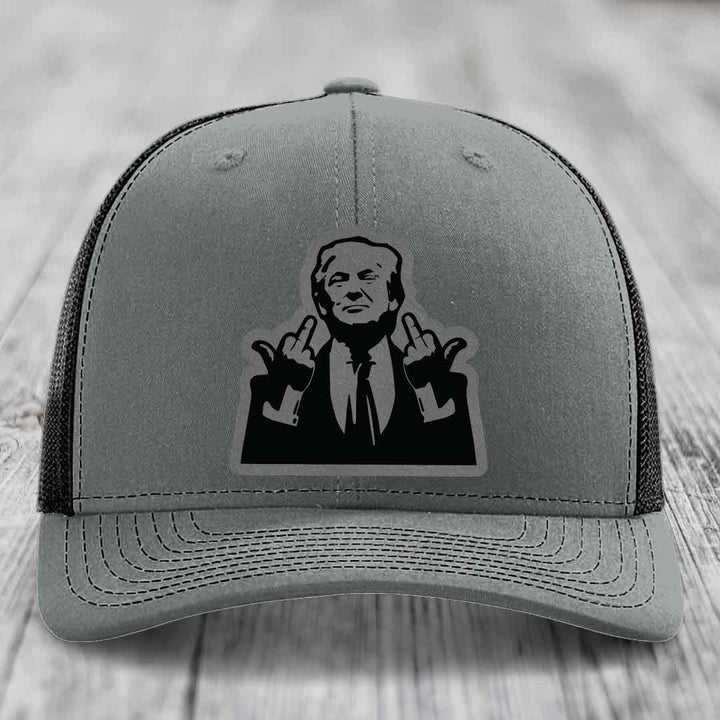 Grey trucker hat with black mesh back and a black leather patch of a man making hand gestures.