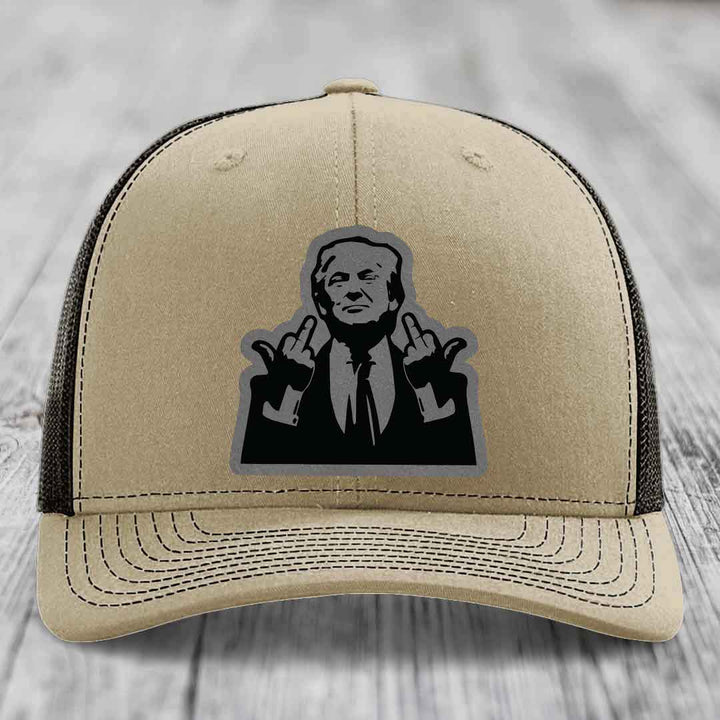 Beige trucker hat with black mesh back and a black-and-grey graphic patch of a man making hand gestures.