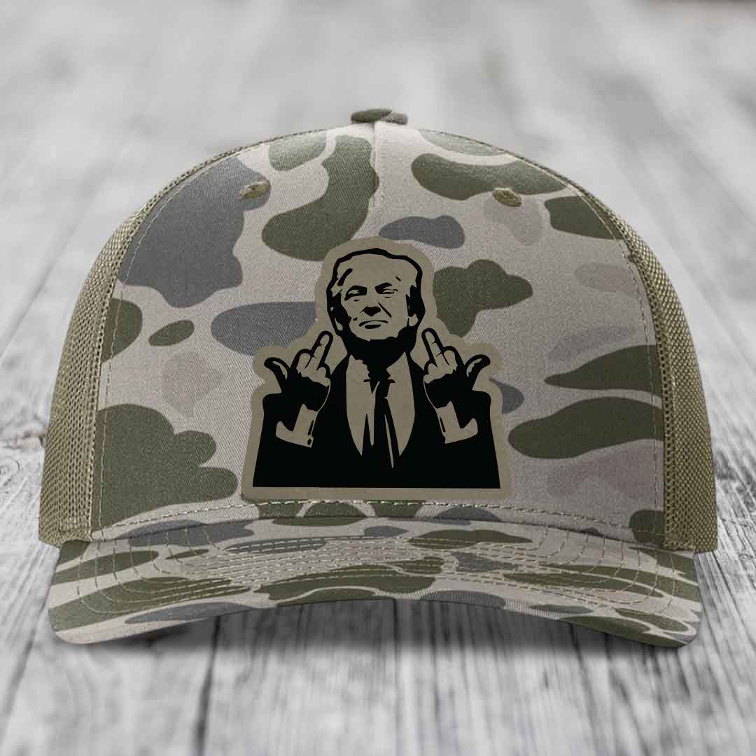 Camouflage trucker hat with black silhouette patch of man giving middle finger gesture.