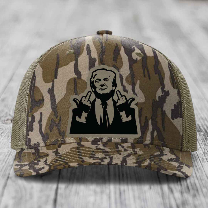 Camouflage trucker hat with black silhouette patch of man giving middle finger gesture.
