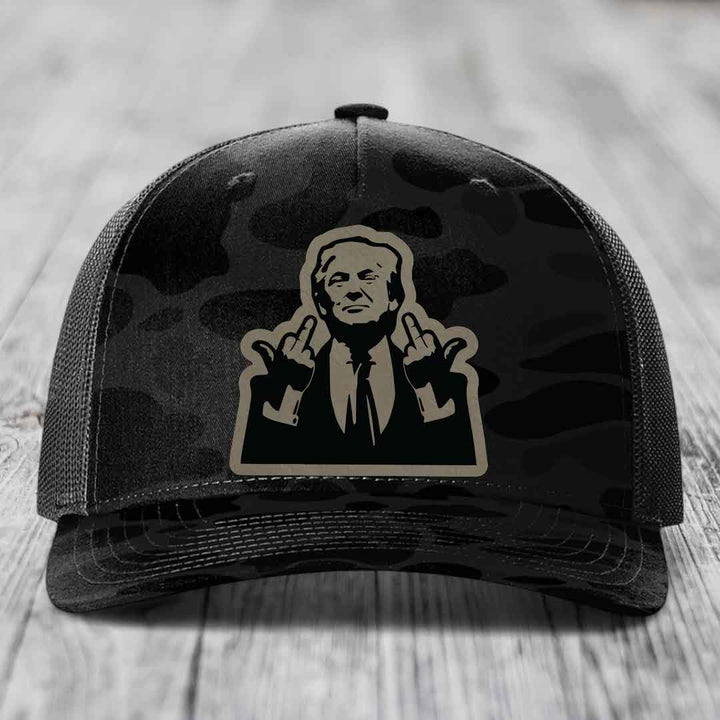 Black camouflage trucker hat with a beige and black patch of a man making rude hand gestures.