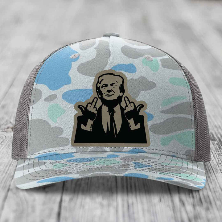 Camouflage trucker hat with black silhouette patch of man giving middle finger gesture.