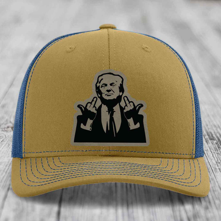 Tan and blue trucker hat with black graphic patch of man making hand gestures.