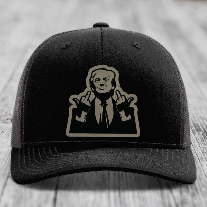 Black trucker hat with beige silhouette patch of a man making rude hand gestures.