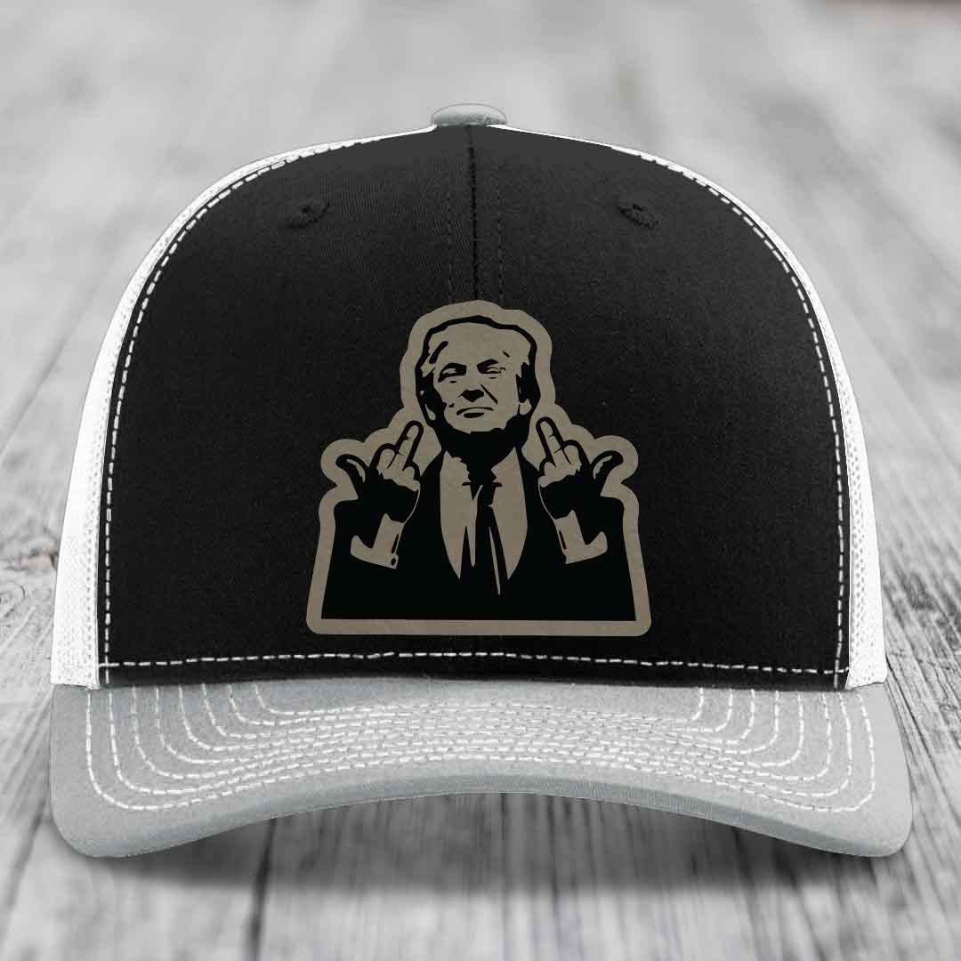 Black and grey trucker hat with white stitching and a beige graphic patch of a man making rude hand gestures.