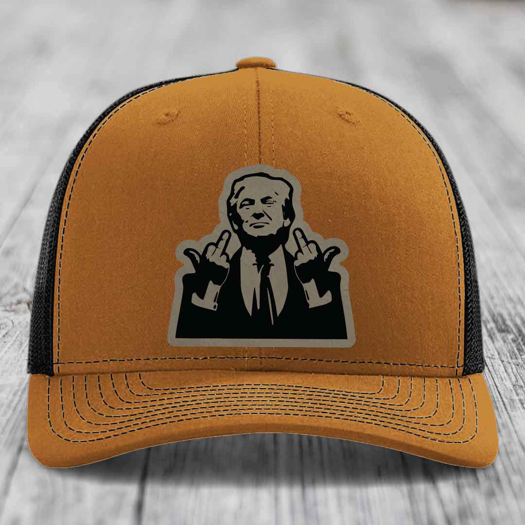 Tan trucker hat with black mesh back and a black-and-grey graphic patch of a man making hand gestures.