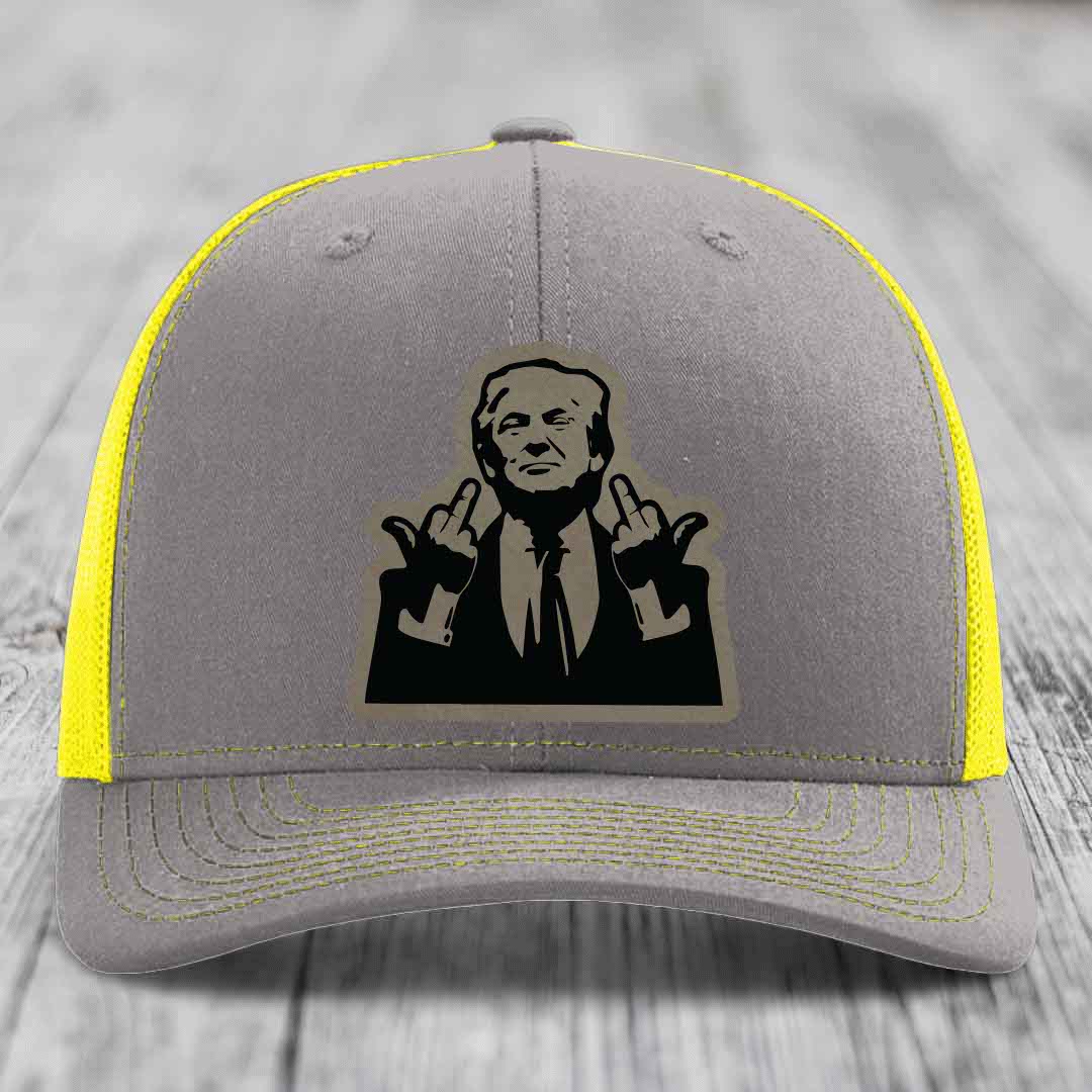 Grey trucker hat with yellow mesh and stitching, featuring a black patch of a man making rude hand gestures.
