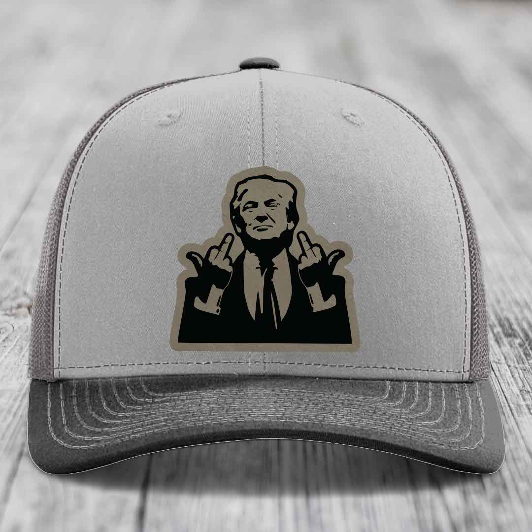 Grey trucker hat with black and tan patch of man giving middle finger gesture.