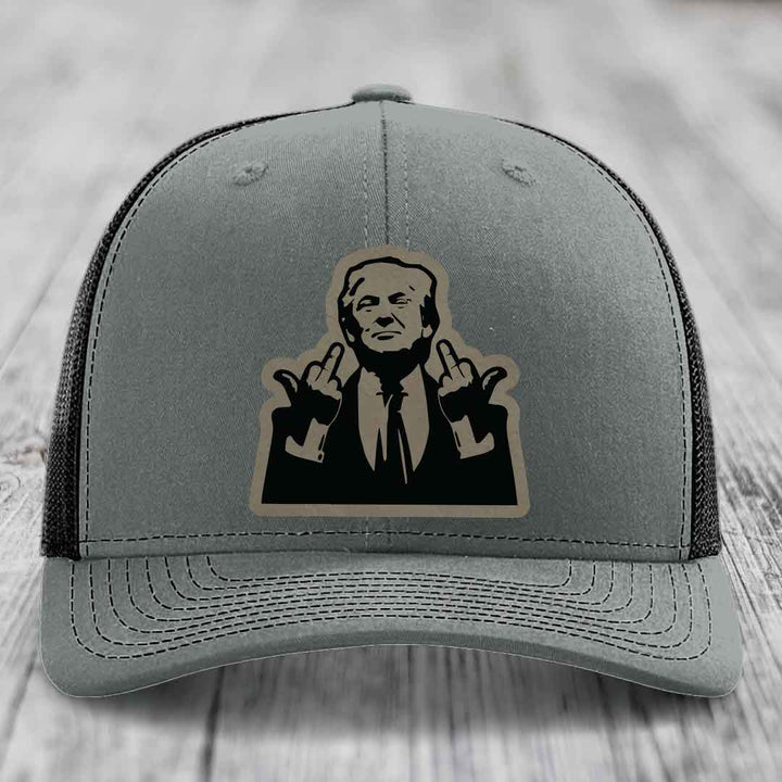 Grey trucker hat with black and tan patch of man giving two middle fingers