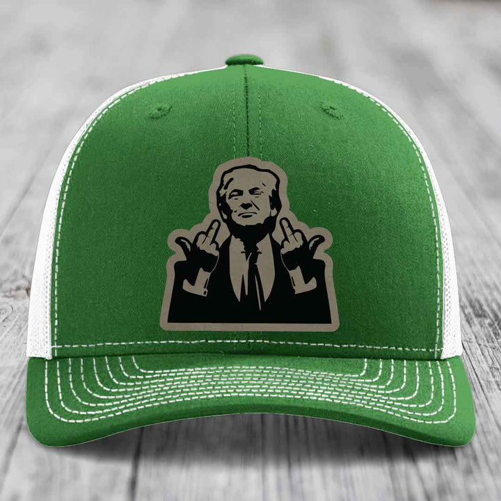 Green trucker hat with white mesh back and stitching, featuring a black and grey patch of a man making hand gestures.
