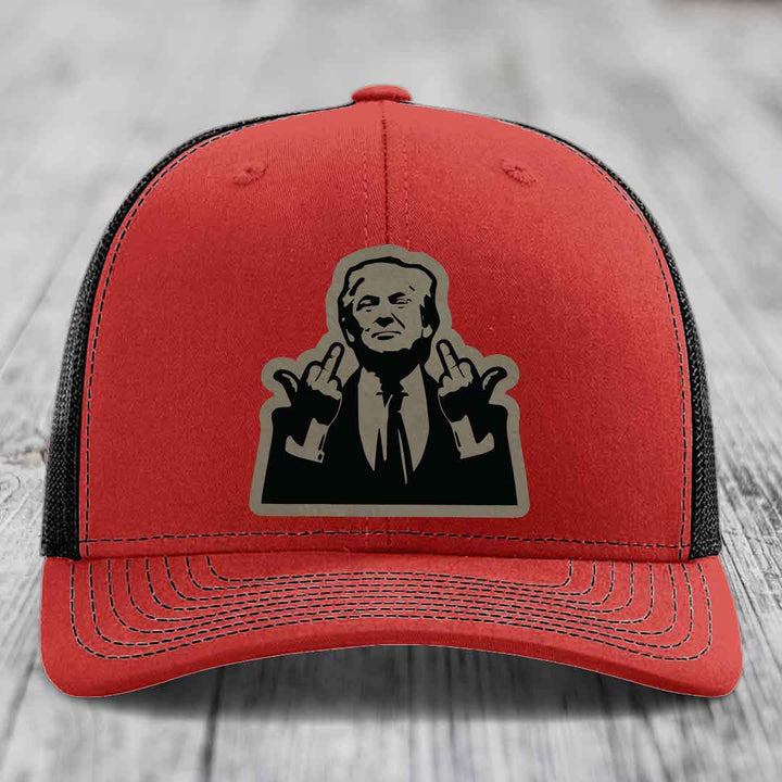 Red trucker hat with black mesh back and a graphic patch of a man making hand gestures.