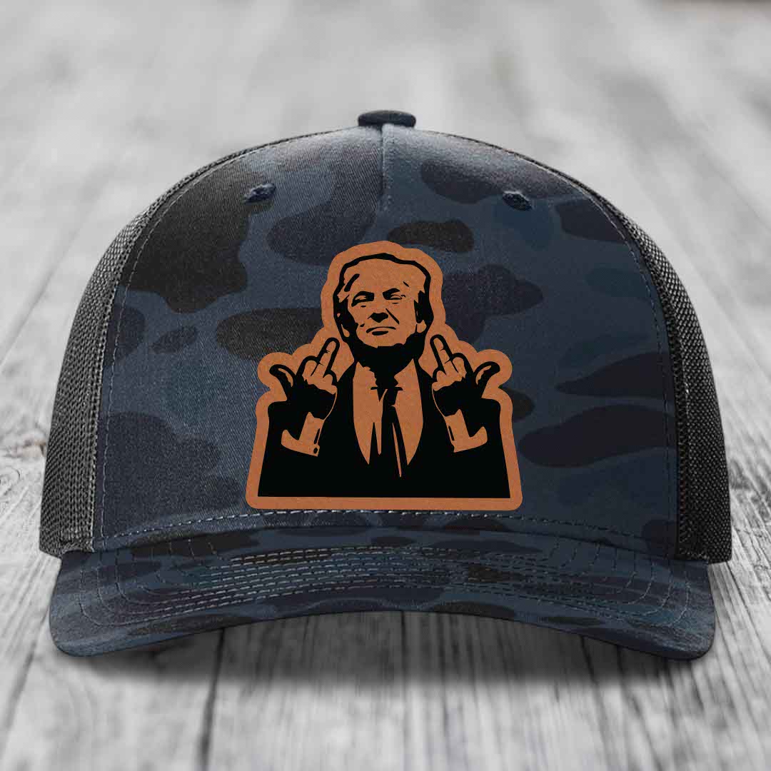 Camouflage trucker hat with a brown leather patch featuring a silhouette of a man making hand gestures.