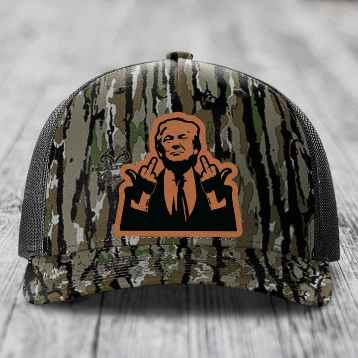 Camouflage trucker hat with orange and black leather patch of man making hand gestures.