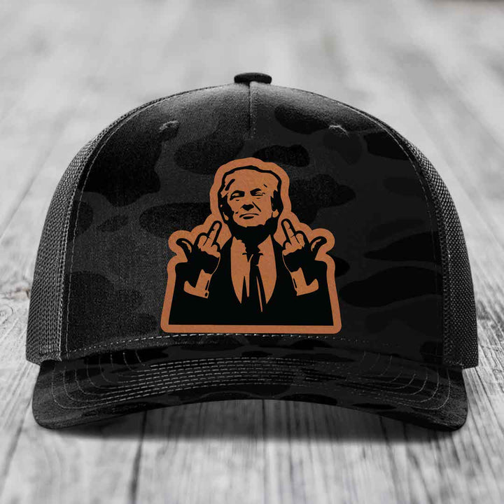 Black camouflage trucker hat with orange leather patch of man giving two middle fingers