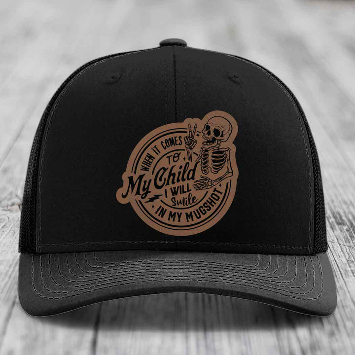 Black trucker hat with brown leather patch featuring skeleton and text &