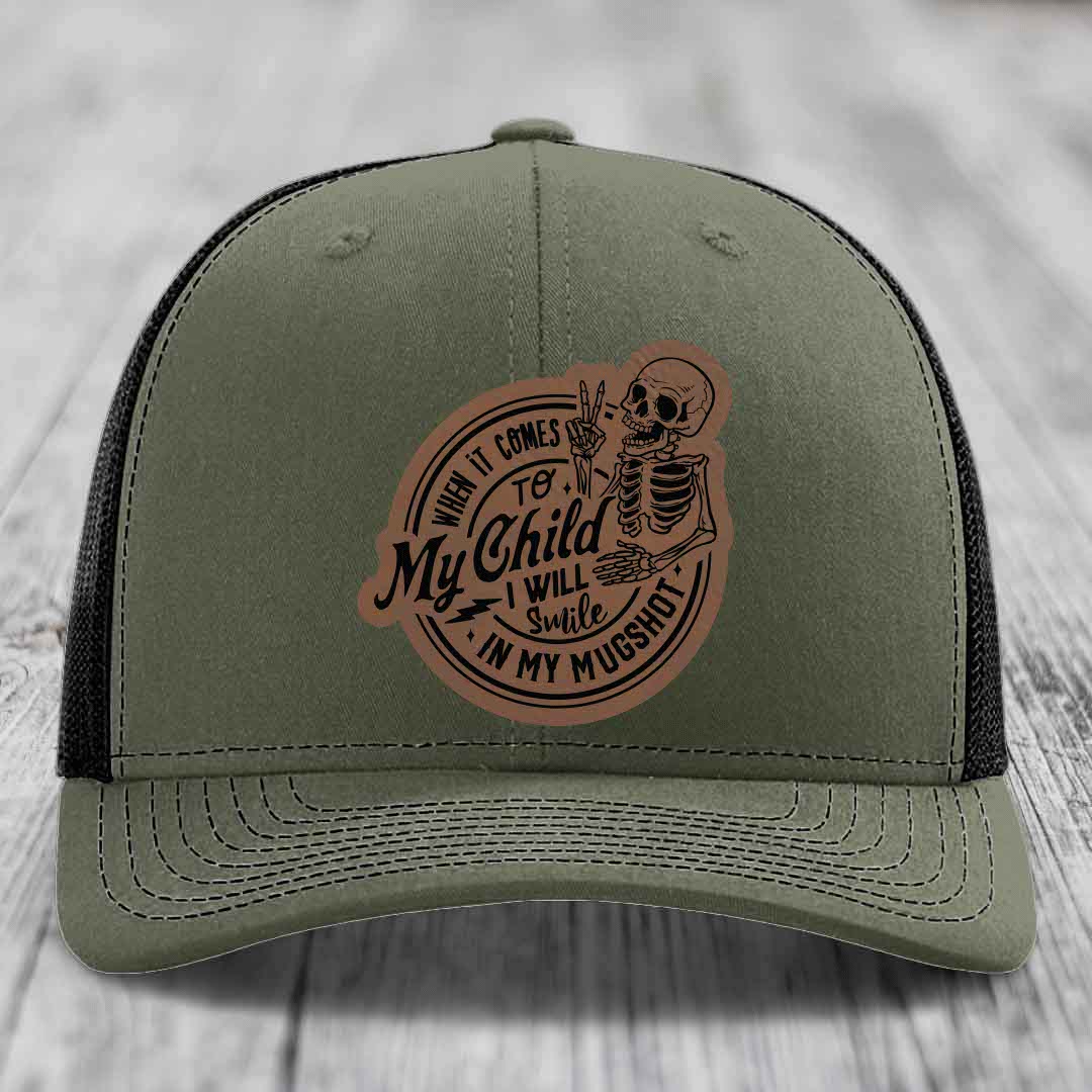 Olive green trucker hat with brown leather patch featuring skeleton and text: &