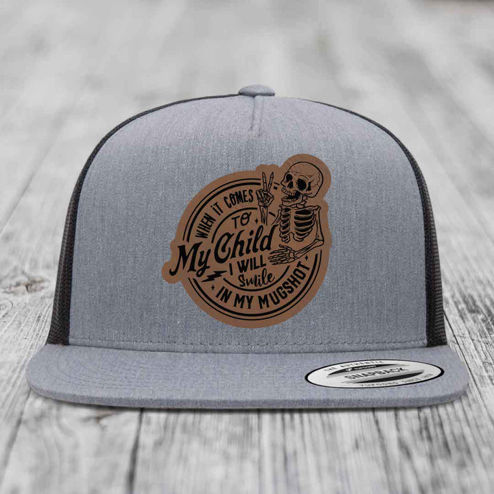 Grey trucker hat with brown leather patch featuring skeleton and text &