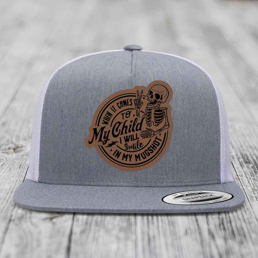 Grey trucker hat with brown leather patch featuring skeleton and text &