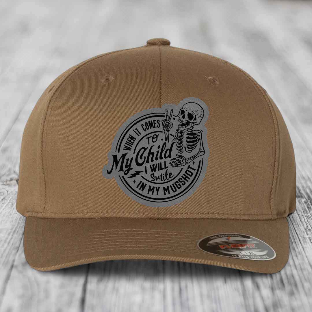 Tan baseball cap with a circular patch featuring a skeleton making a peace sign and the text &