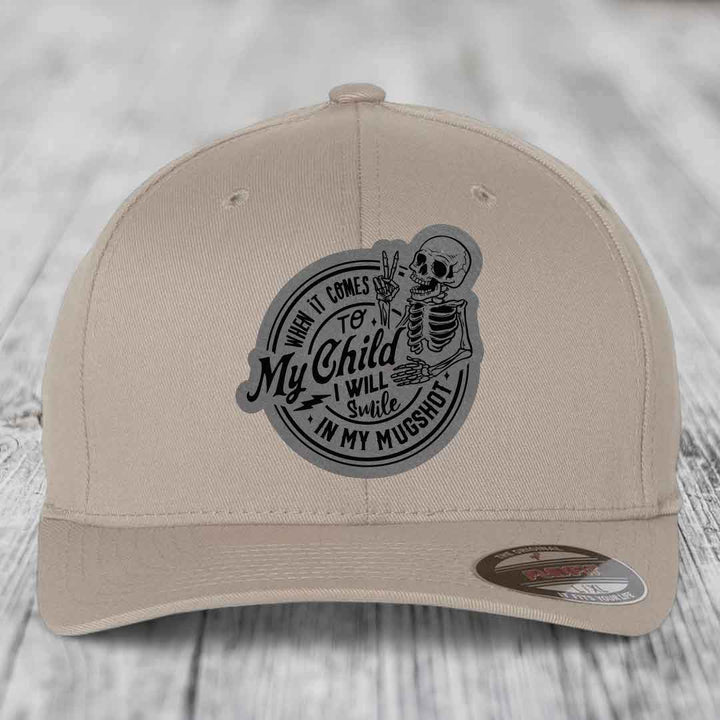 Beige baseball cap with black and gray circular patch featuring skeleton holding peace sign and text &