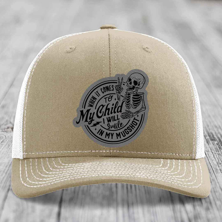 Tan trucker hat with black and gray patch featuring skeleton holding peace sign and text &