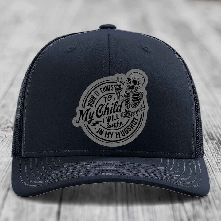 Black trucker hat with grey circular patch featuring skeleton and text &