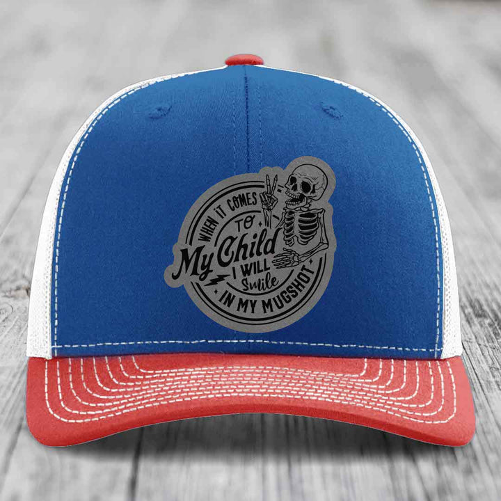 Blue and red trucker hat with grey skeleton patch reading &