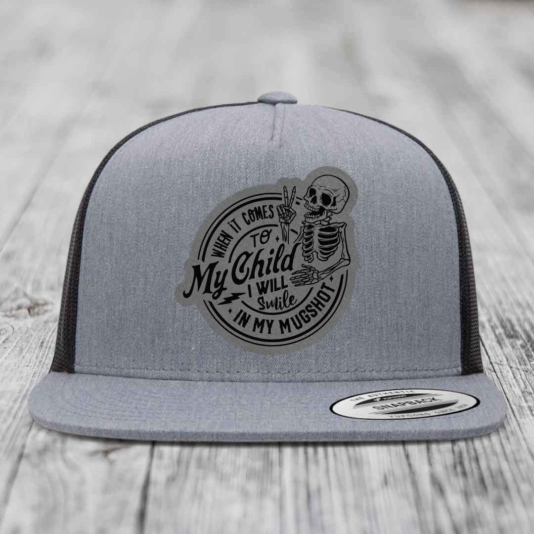 Grey trucker hat with black mesh back and a circular patch featuring a skeleton making a peace sign and the text &
