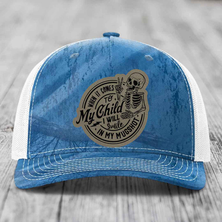 Blue trucker hat with white mesh back and a skull patch that reads &