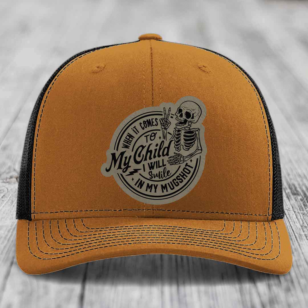 Tan trucker hat with black mesh back and a circular skull patch reading &