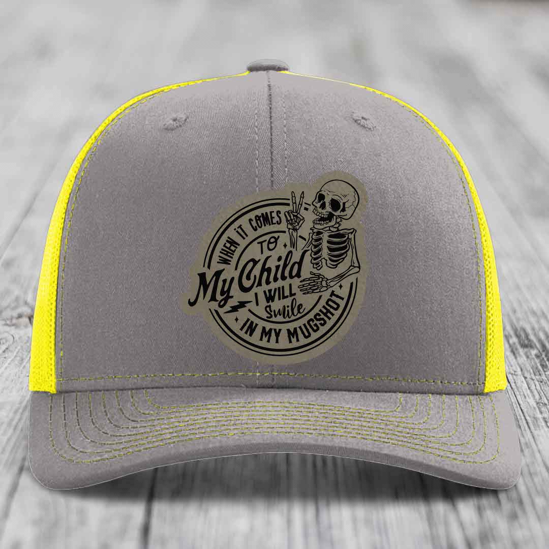 Grey trucker hat with yellow mesh and stitching, featuring a skeleton patch that reads &