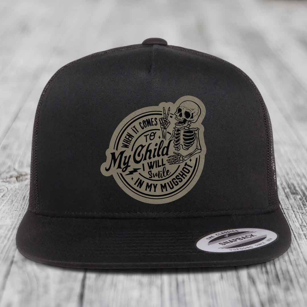 Black snapback hat with beige circular patch featuring a skeleton holding up two fingers and the text &