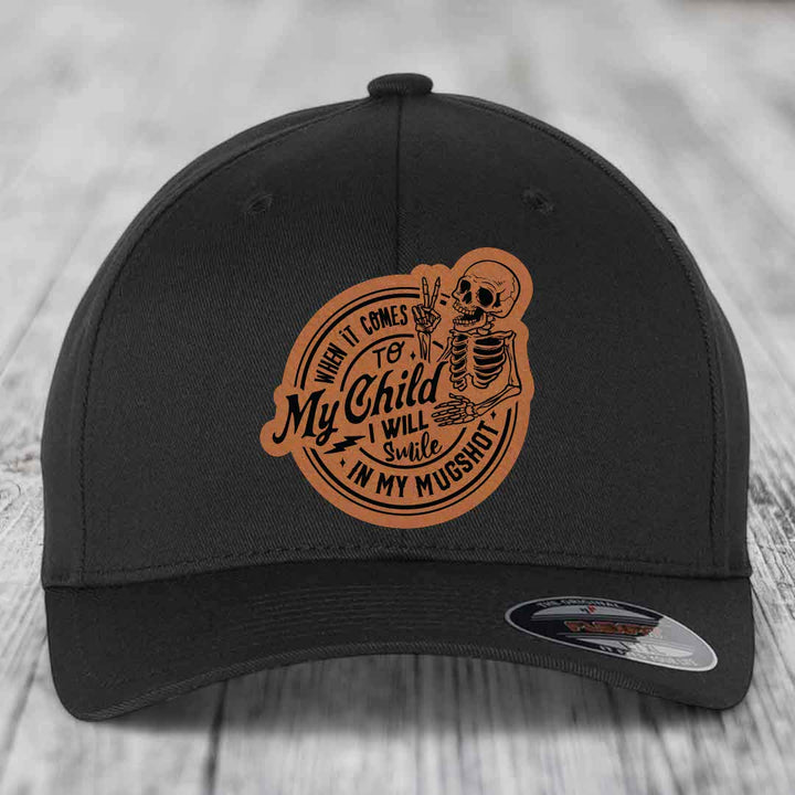 Black baseball cap with brown leatherette patch featuring skeleton holding peace sign and text &
