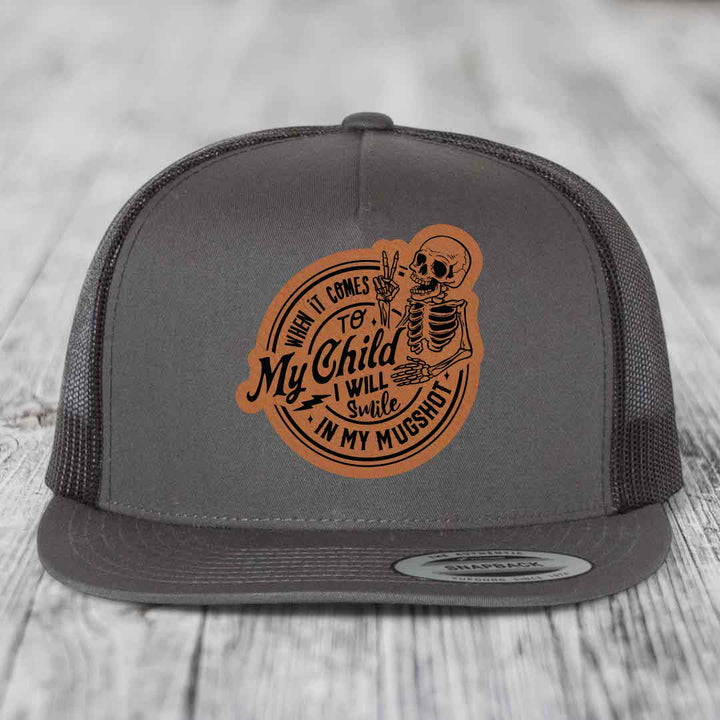 Grey trucker hat with brown leather patch featuring skeleton and text &