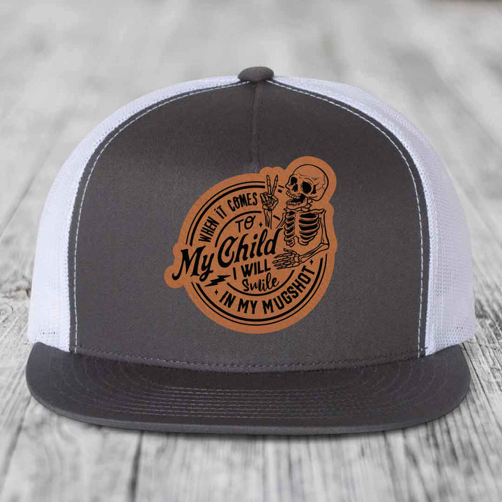 Grey trucker hat with brown leatherette patch featuring skeleton and text &