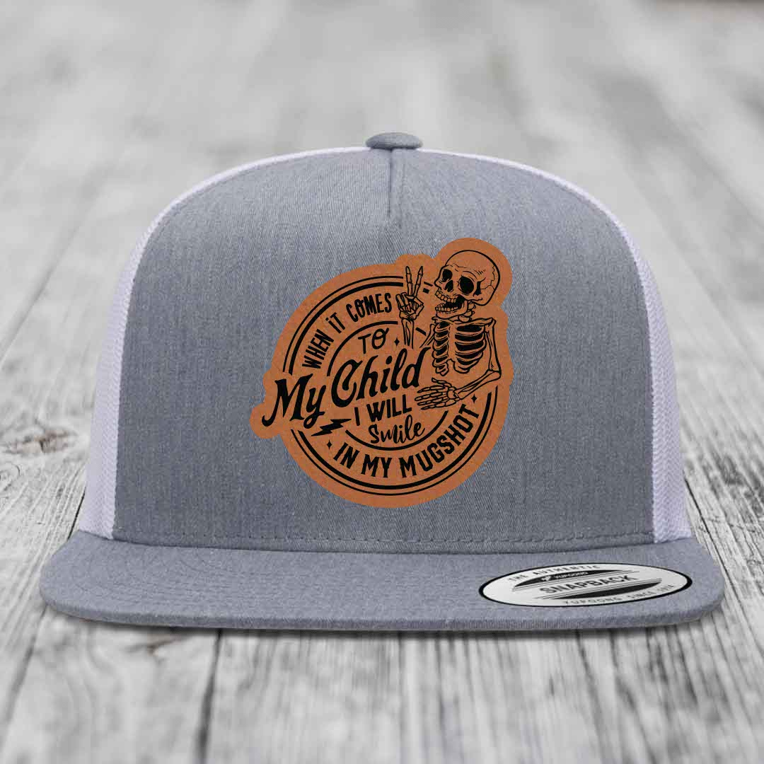 Grey trucker hat with brown leather patch featuring skeleton and text &