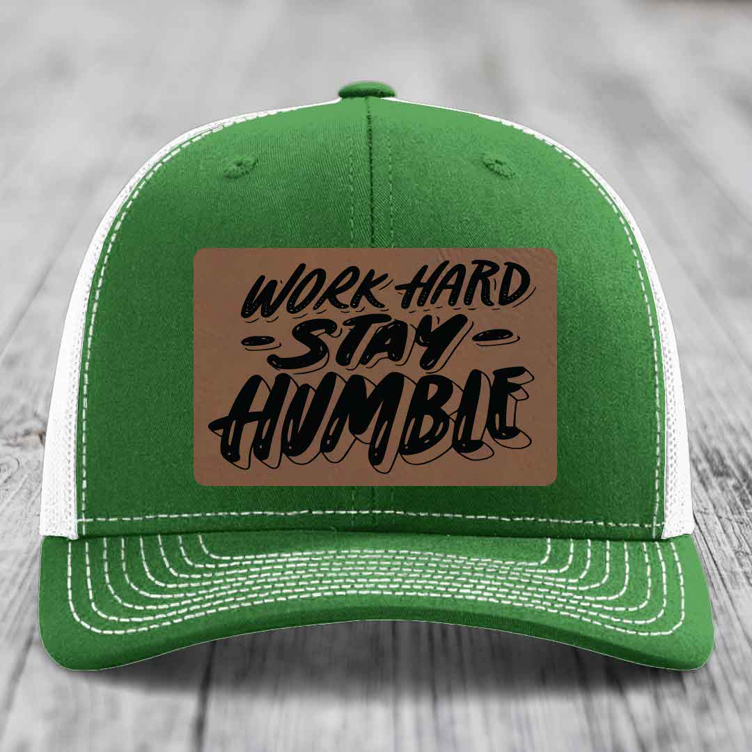 Green trucker hat with white mesh back and brim, featuring a brown leatherette patch that reads &