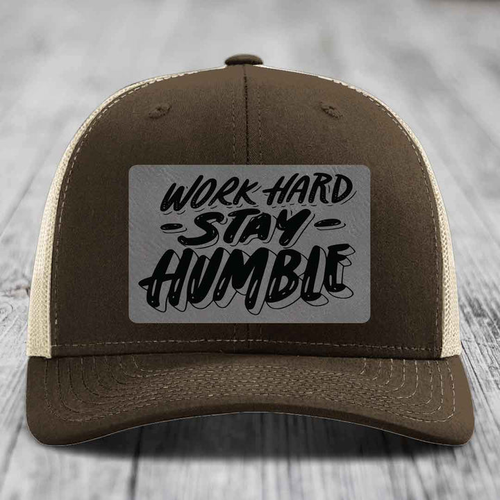 Brown trucker hat with beige mesh back and gray rectangular patch that reads &