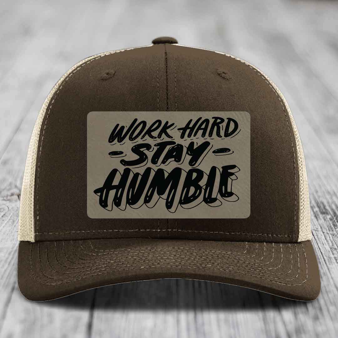 Brown trucker hat with beige mesh back and black embroidered patch reading &
