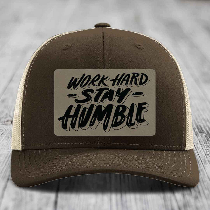 Brown trucker hat with beige mesh back and black embroidered patch reading &