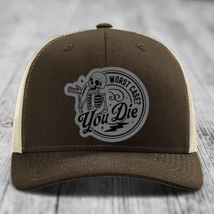 Brown trucker hat with beige mesh back and a circular skull patch that reads &