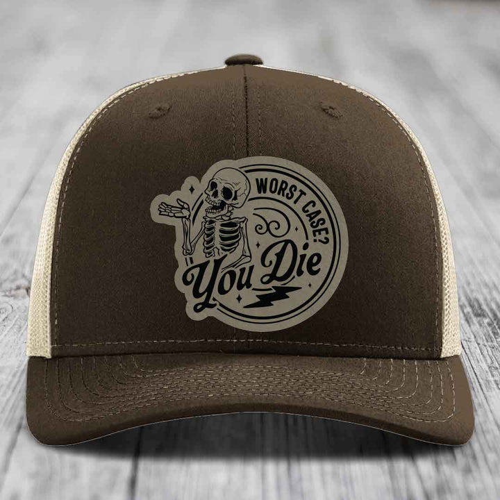 Brown trucker hat with beige mesh back and a circular skull patch that reads &