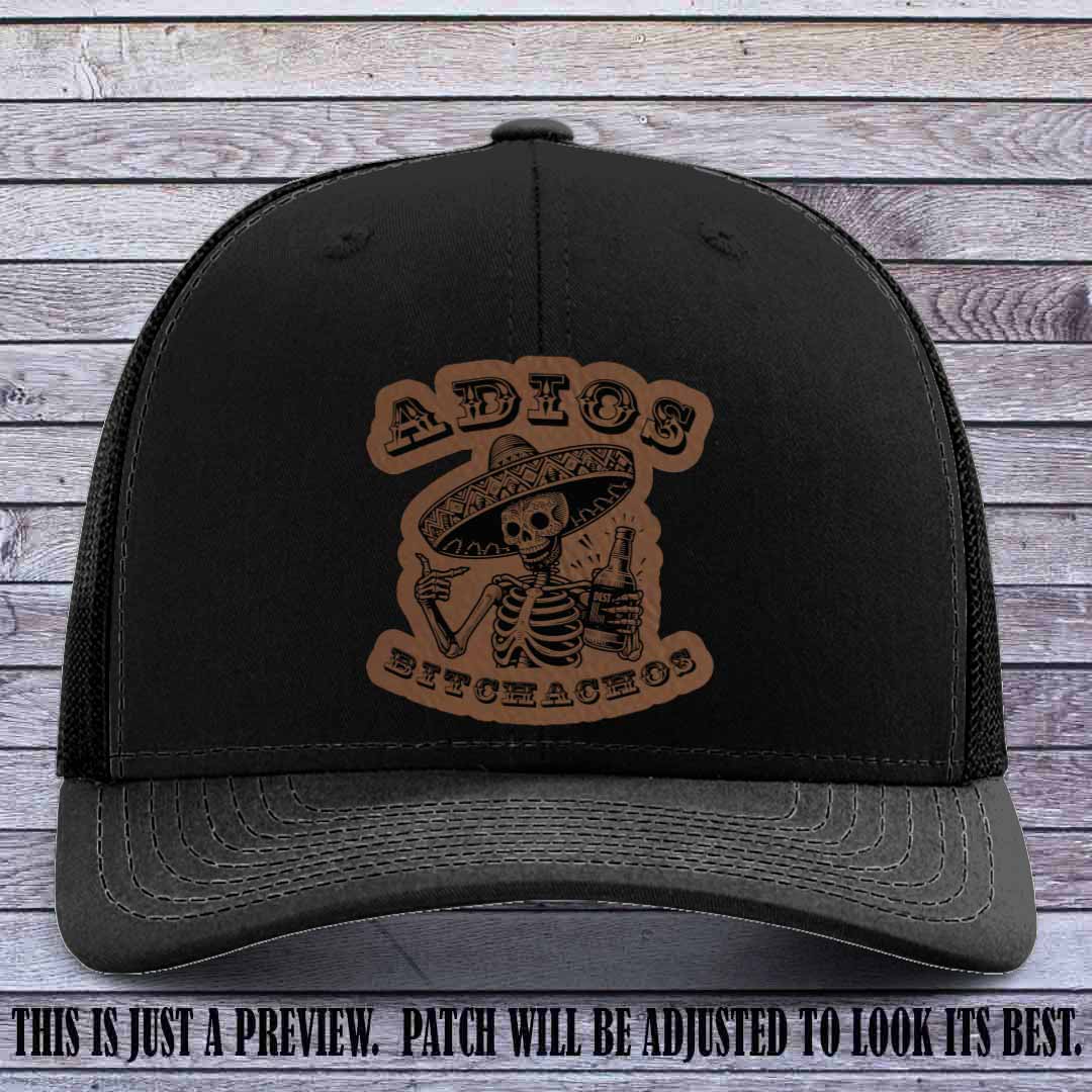 Dark brown leather patch on Black Richardson 112 trucker hat featuring “Adios Bitchachos” skeleton design.